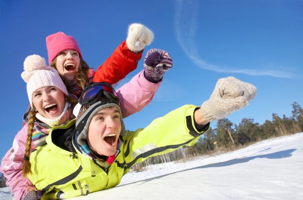 Teens sliding down snow-covered hill in winter
