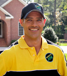 Smiling Mosquito Joe technician wearing black hat with a black and yellow mosquito joe shirt